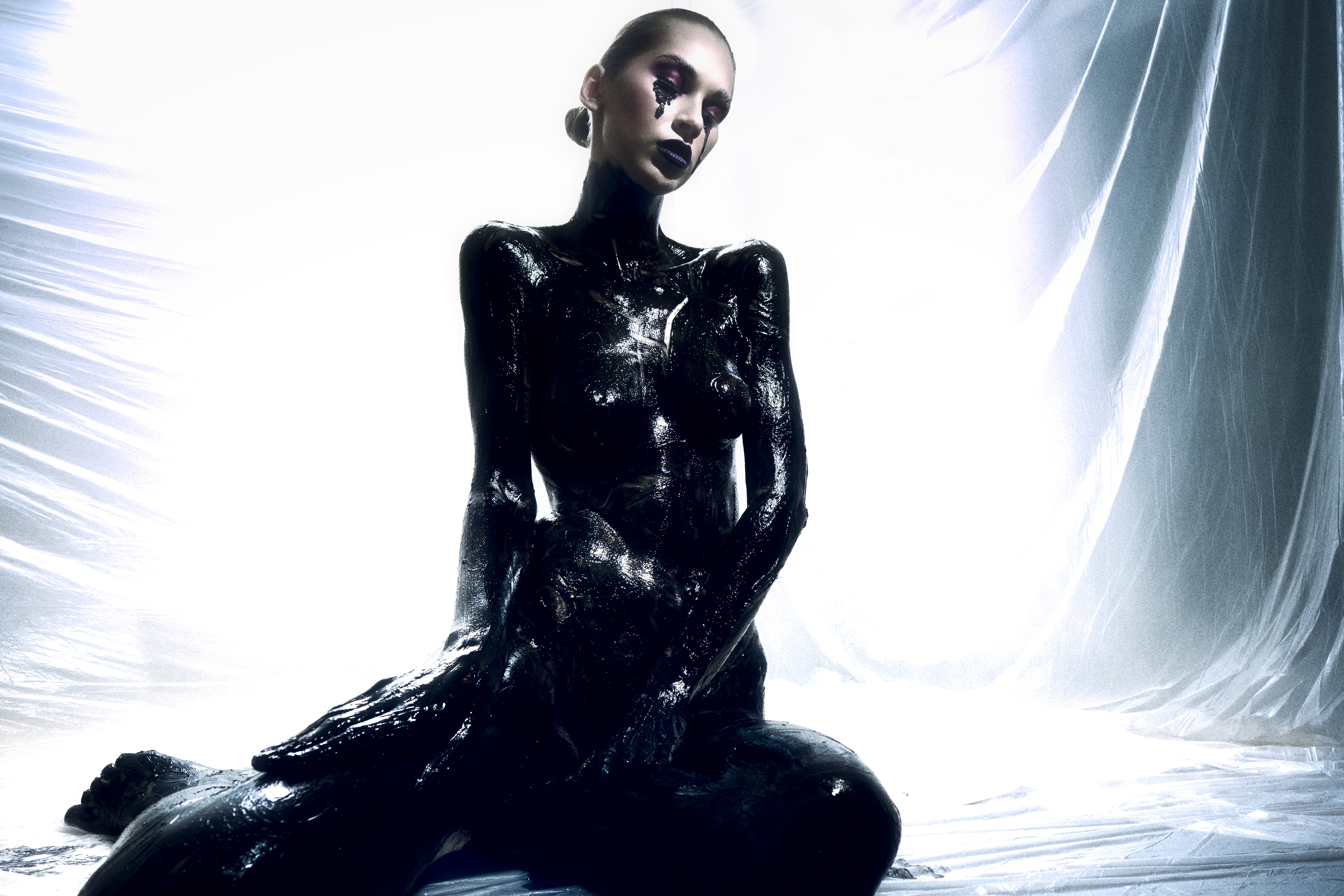 fine art conceptual photography — figure covered in black paint crouching against translucent plastic drapes, Black Gold series, Toronto photographer Daniyar Sadykov